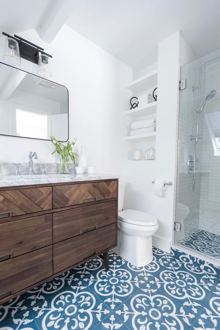 Bright bathroom with dark wood vanity, white fixtures, and blue patterned tile floor.