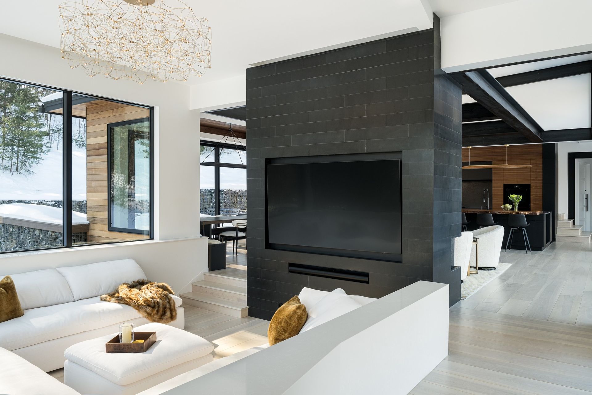 Modern living room with white sofas and a large black fireplace wall
