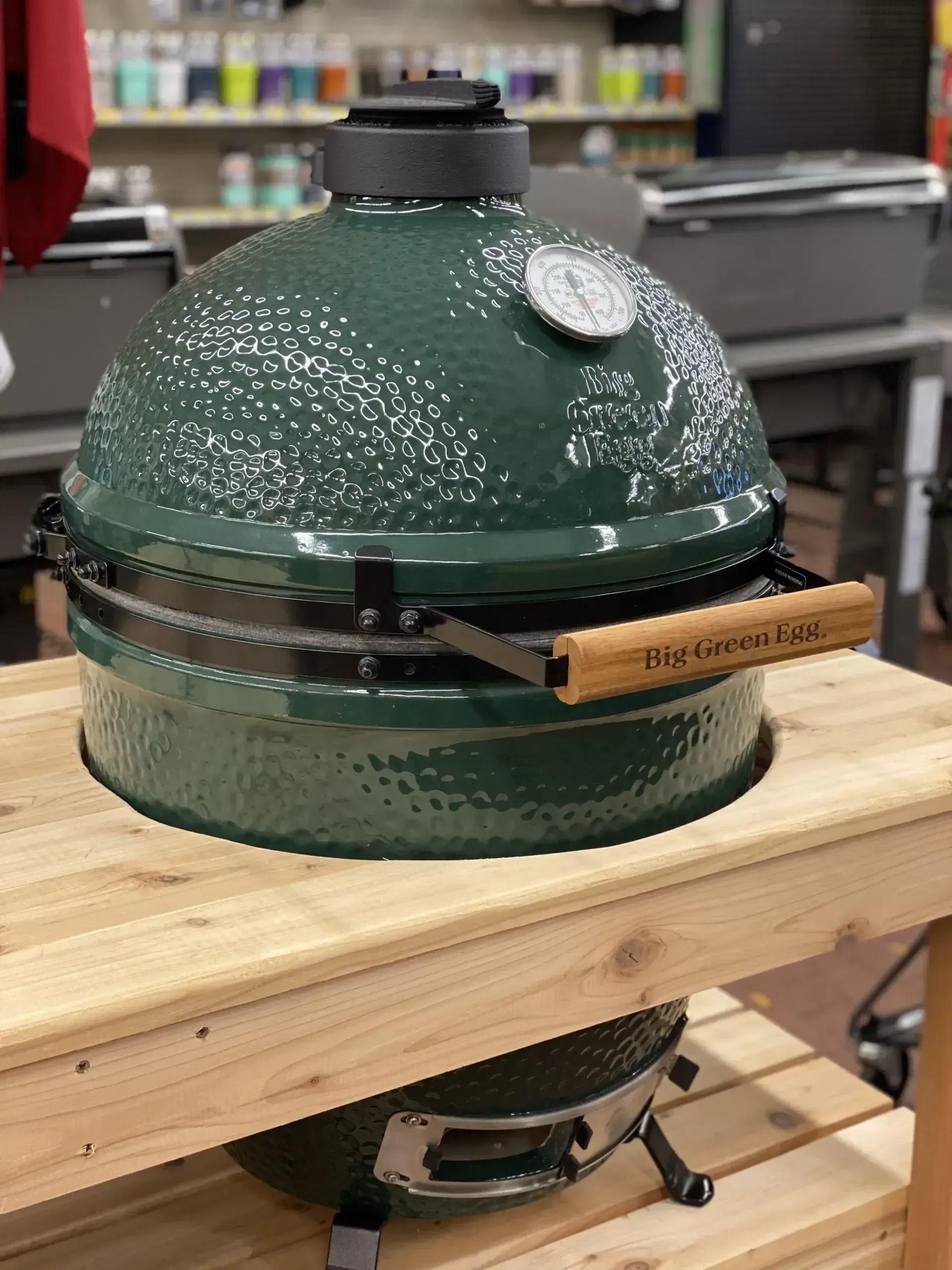 A green grill is sitting on top of a wooden table.