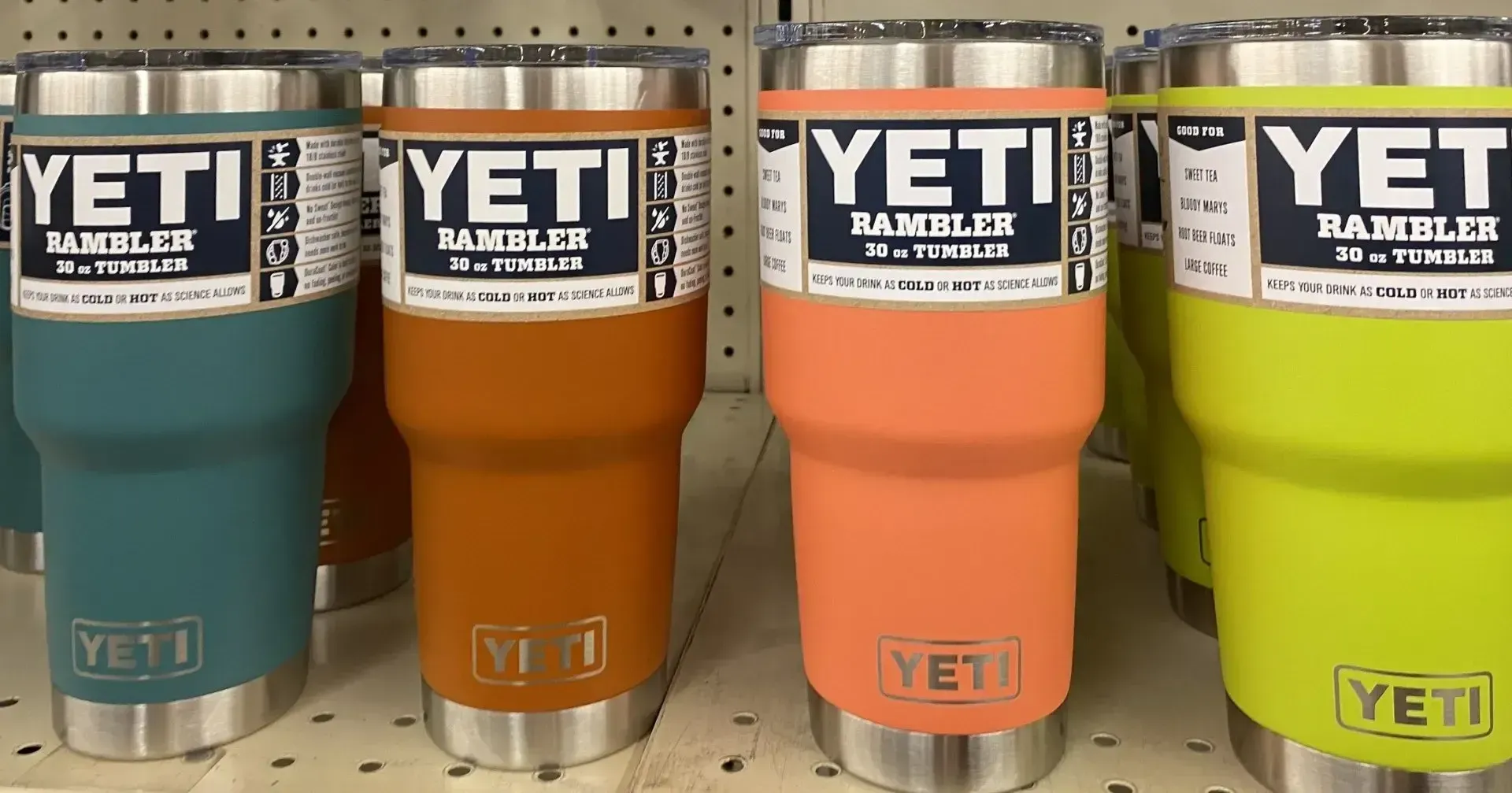 Four different colored yeti tumblers are lined up on a shelf.
