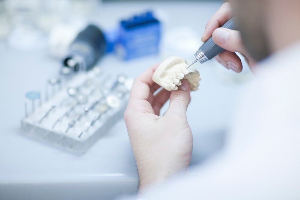 A Dentist is Working on a Dental Model With a Drill — Complete Denture Clinic in Kanwal, NSW