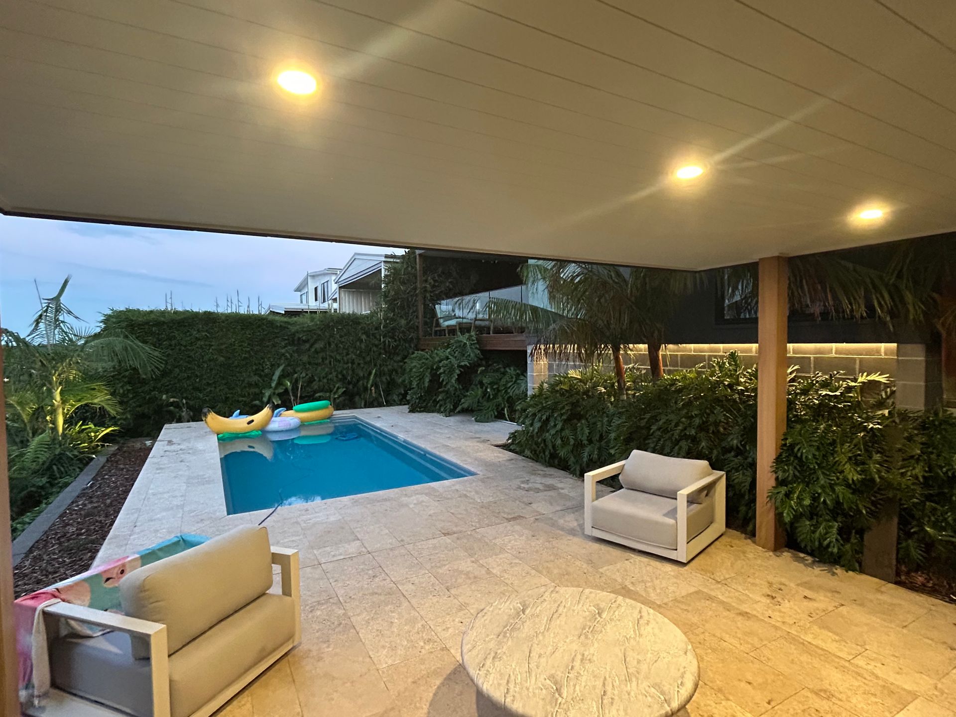 Poolside patio with pool, two armchairs, a round table, and lush greenery — SparkSafe Electrical in Dapto, NSW