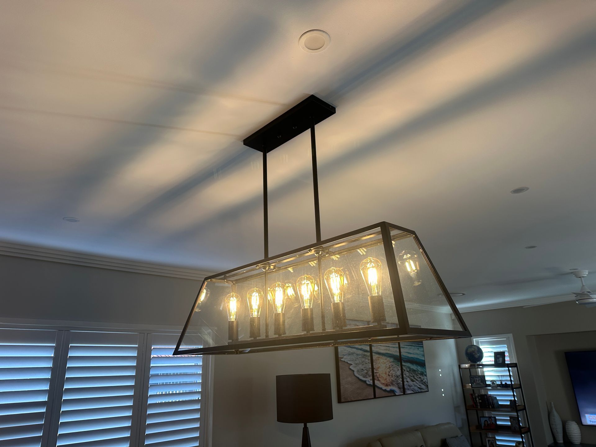 Modern Rectangular Glass Chandelier Hanging in a Softly Lit Room — SparkSafe Electrical in Bulli, NSW