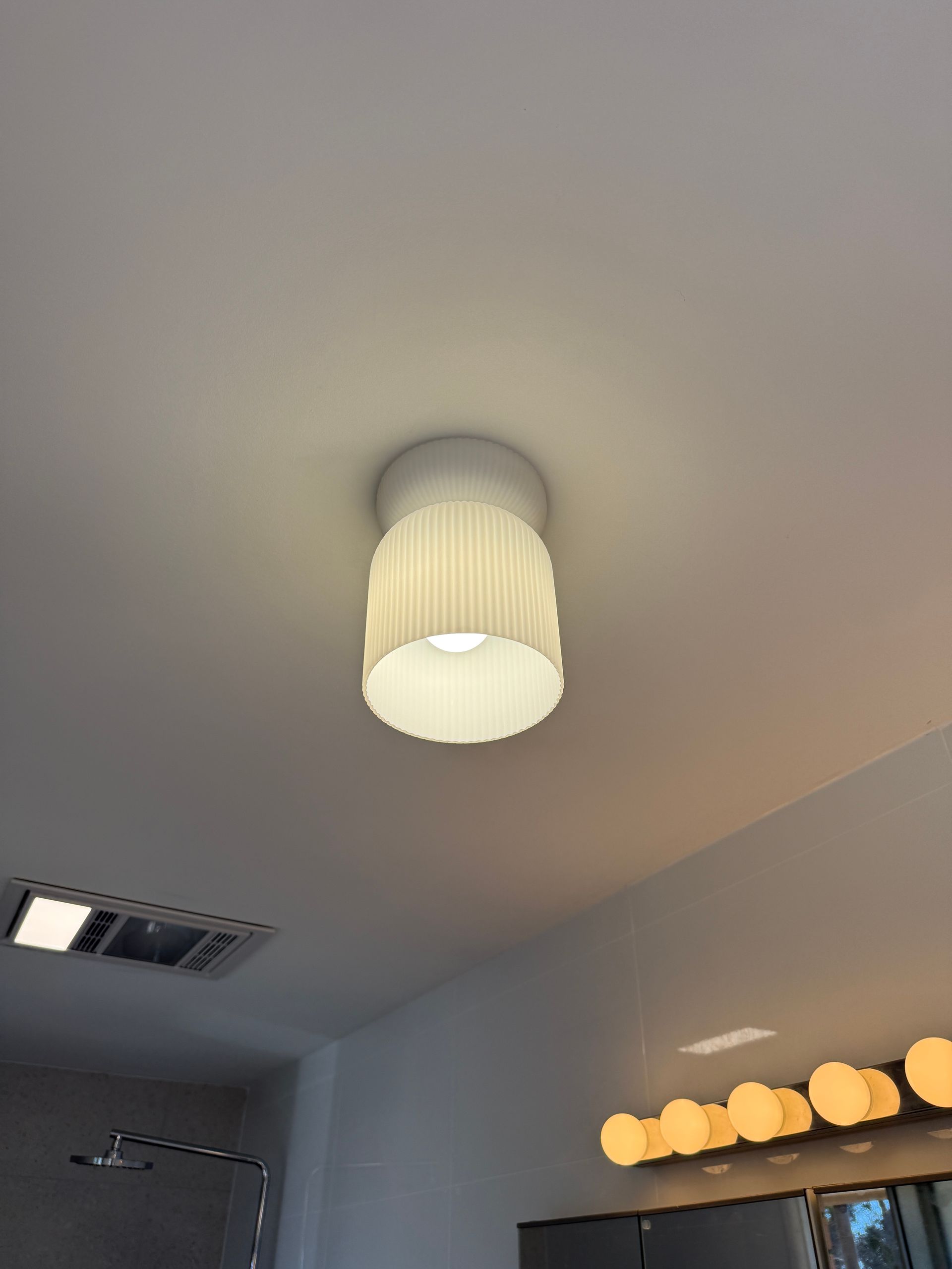 Ceiling Light With a White Ribbed Shade in a Gray Bathroom or Vanity Area — SparkSafe Electrical in Bulli, NSW