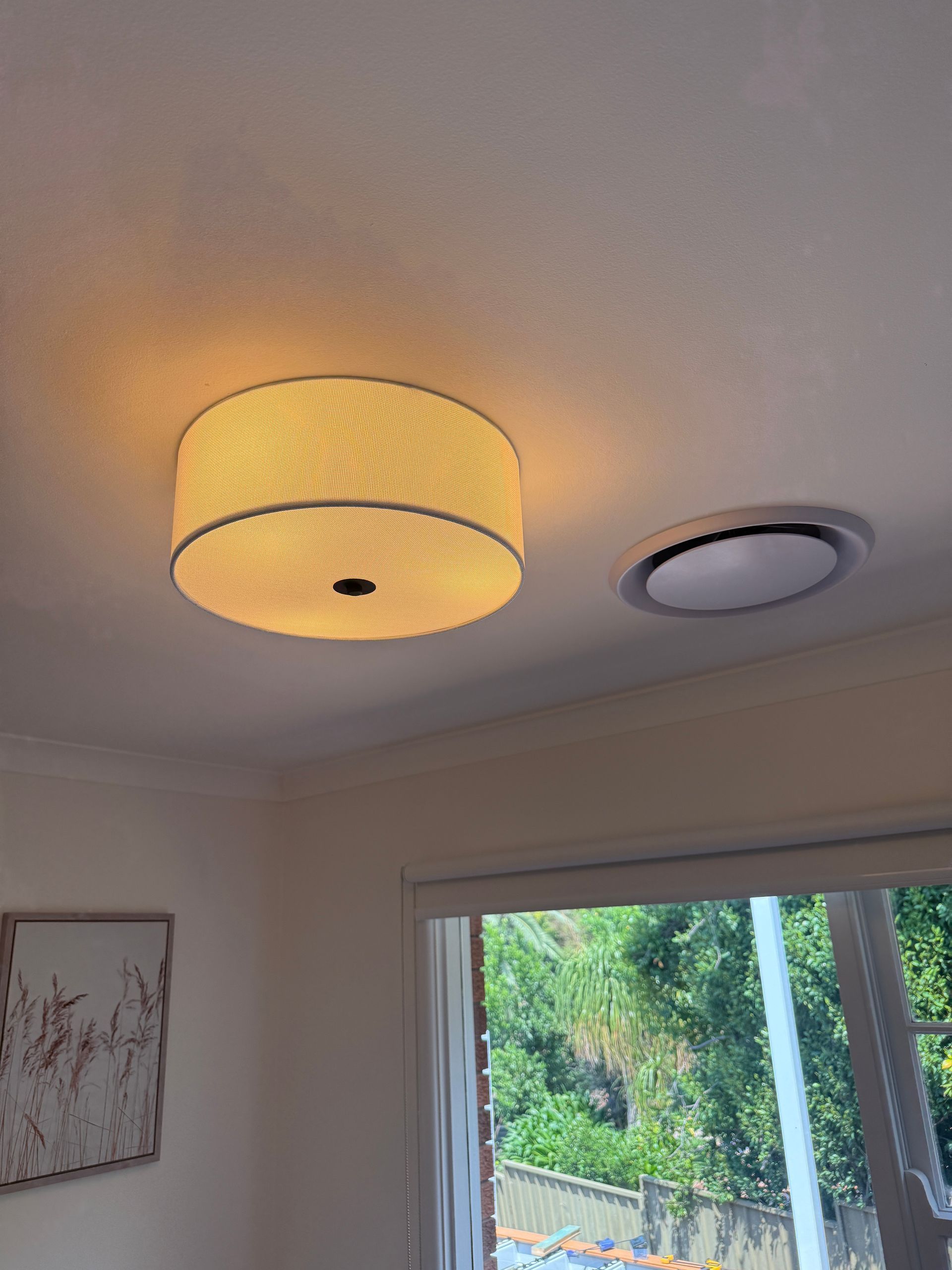 A Round, Illuminated Ceiling Light Fixture Next to a Smaller, Recessed Ceiling — SparkSafe Electrical in Dapto, NSW