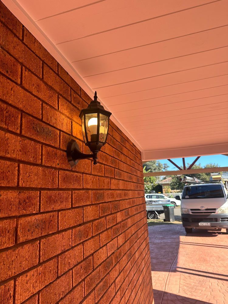 Brick Wall With Lantern Sconce by a Covered Driveway — SparkSafe Electrical in Bulli, NSW