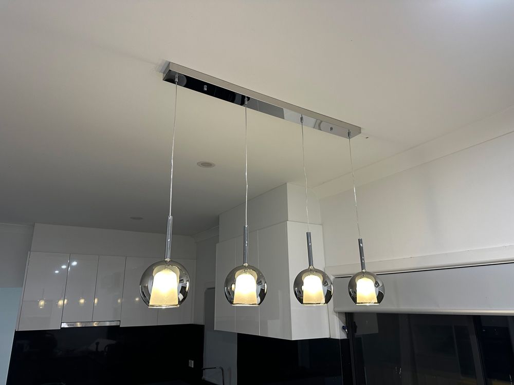 Four Pendant Lights Hanging Over a Modern Kitchen Island — SparkSafe Electrical in Bulli, NSW