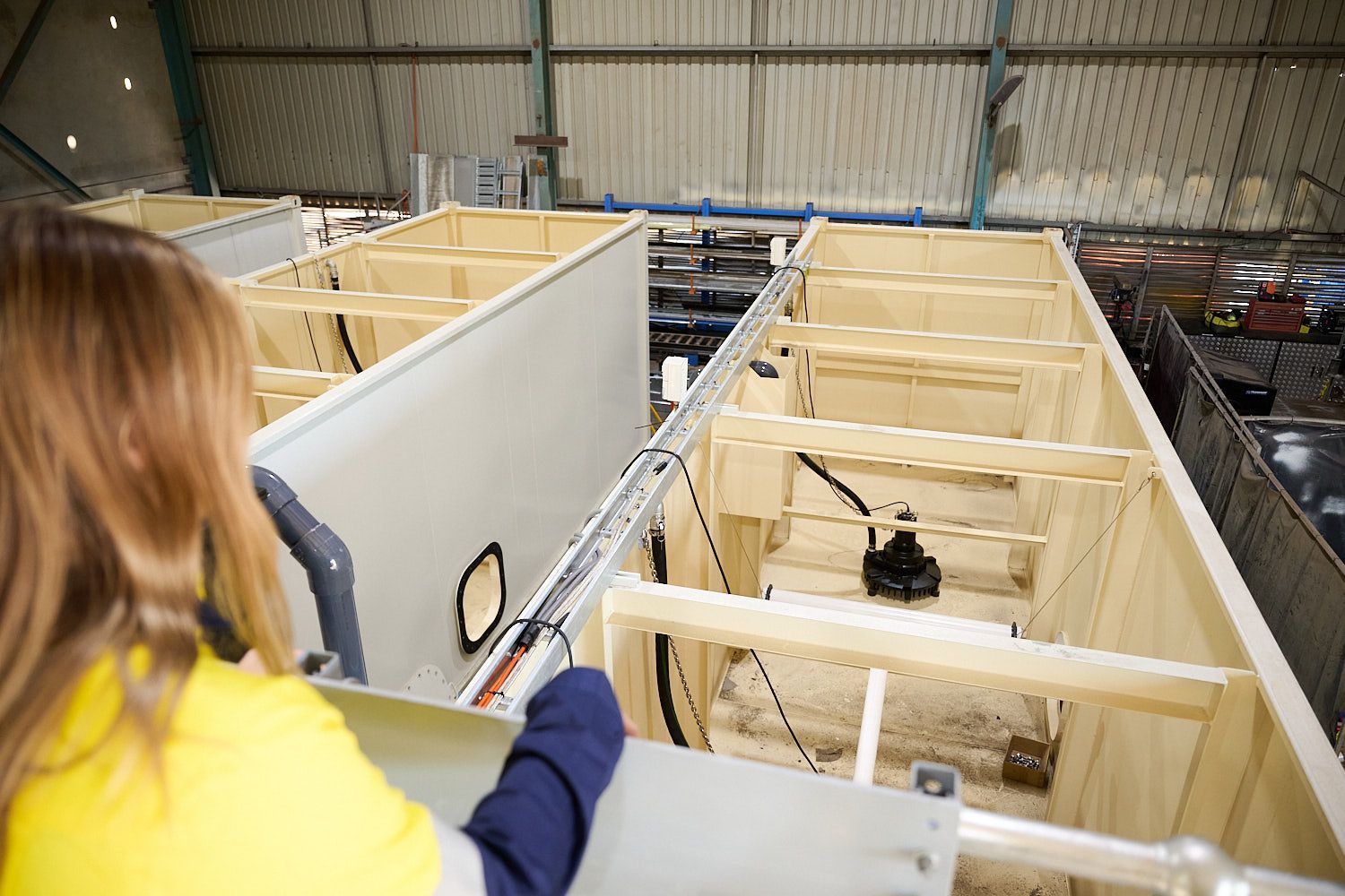 A person looking at metal structures inside a warehouse.