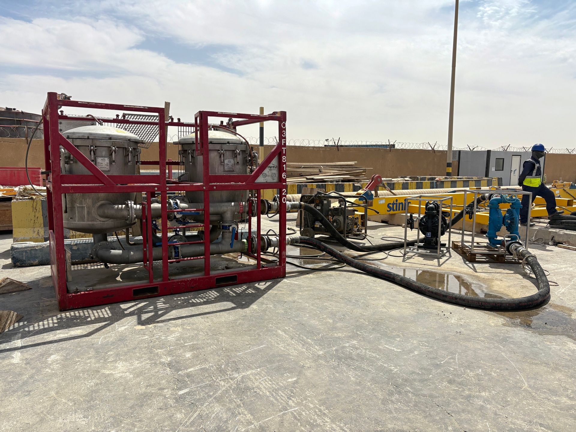 Workers operate Centurion drilling equipment and hoses at an industrial site under a bright sky.