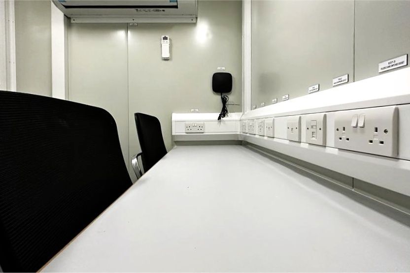 White workspace with electrical outlets, two chairs, and a telephone.