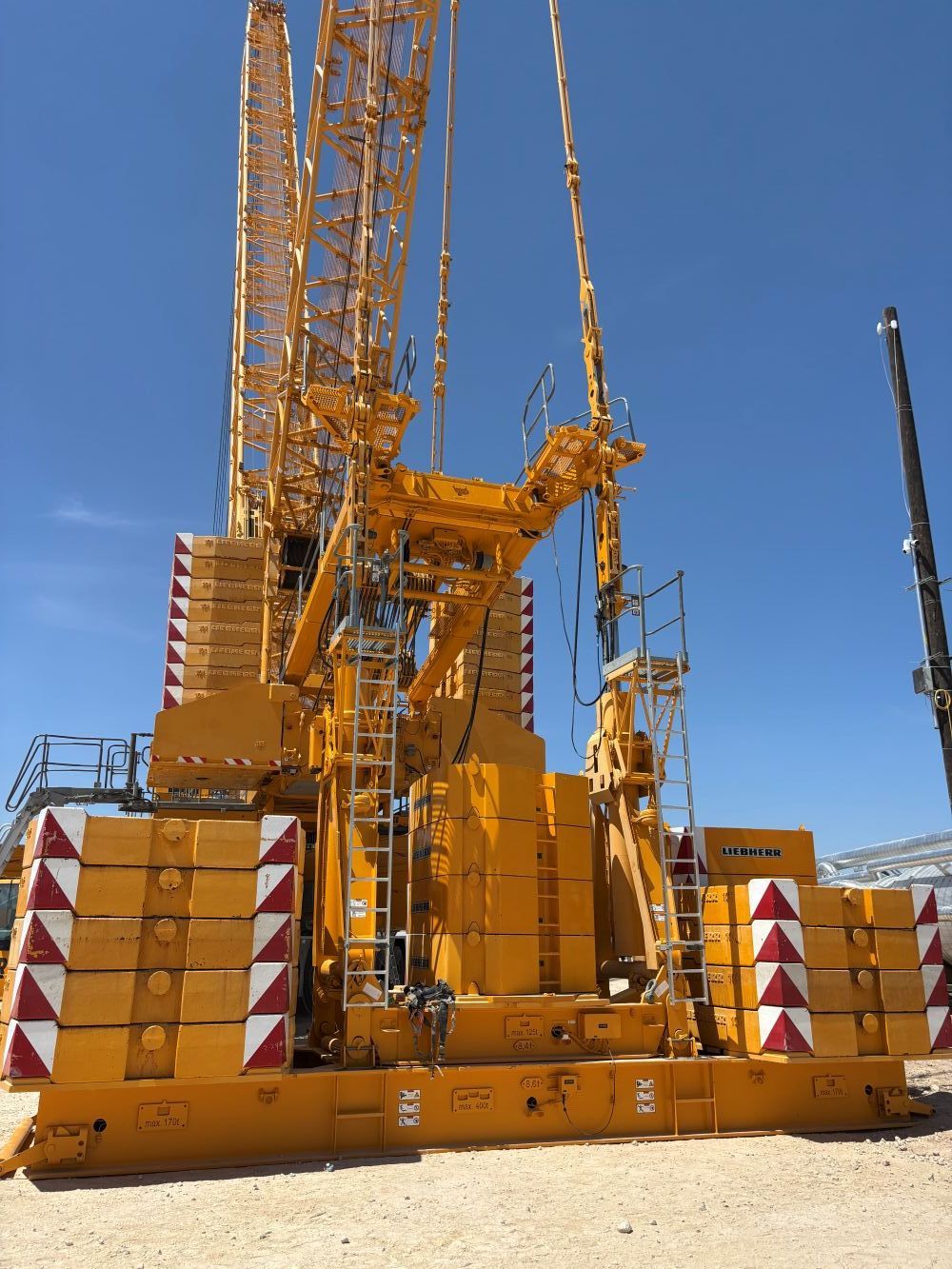 Yellow Trand Centurion crane at an industrial site under a clear blue sky