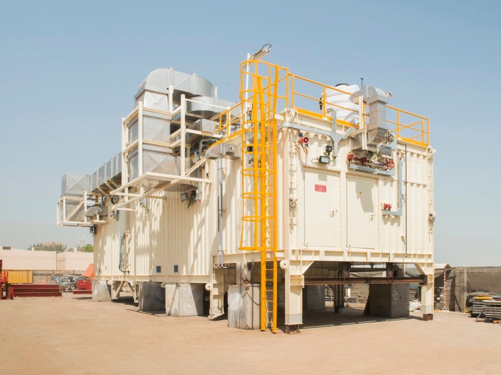 Large industrial beige machine with yellow access ladders in a desert setting.