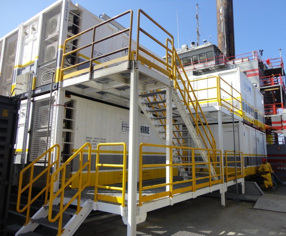 White and yellow industrial building with stairs and metal railings.
