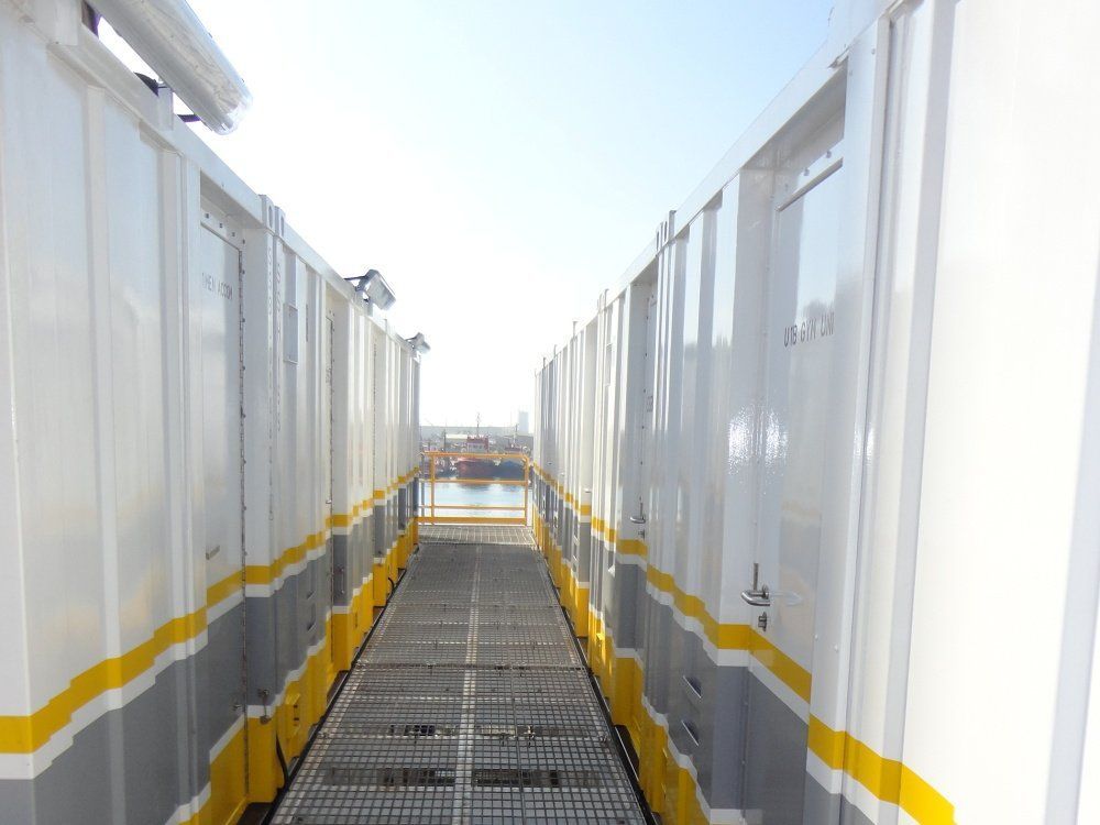 Narrow walkway between white structures with yellow and gray accents.