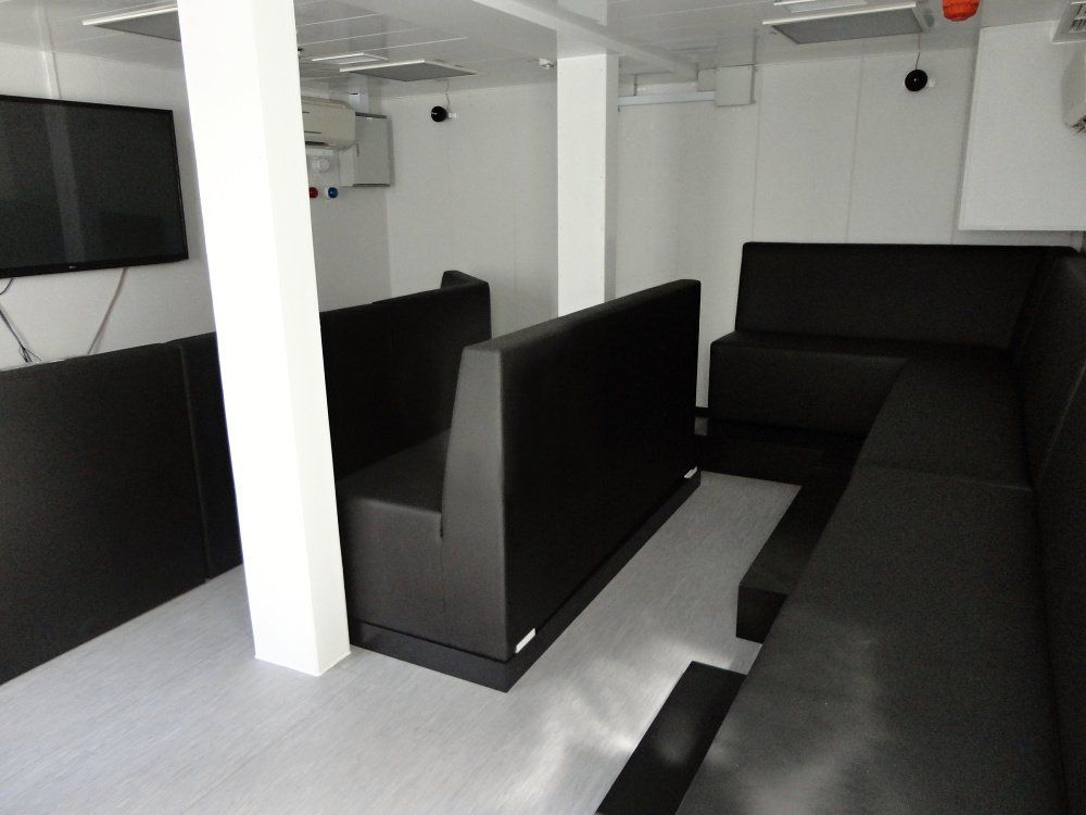 Interior room with black seating, a TV, and white pillars.