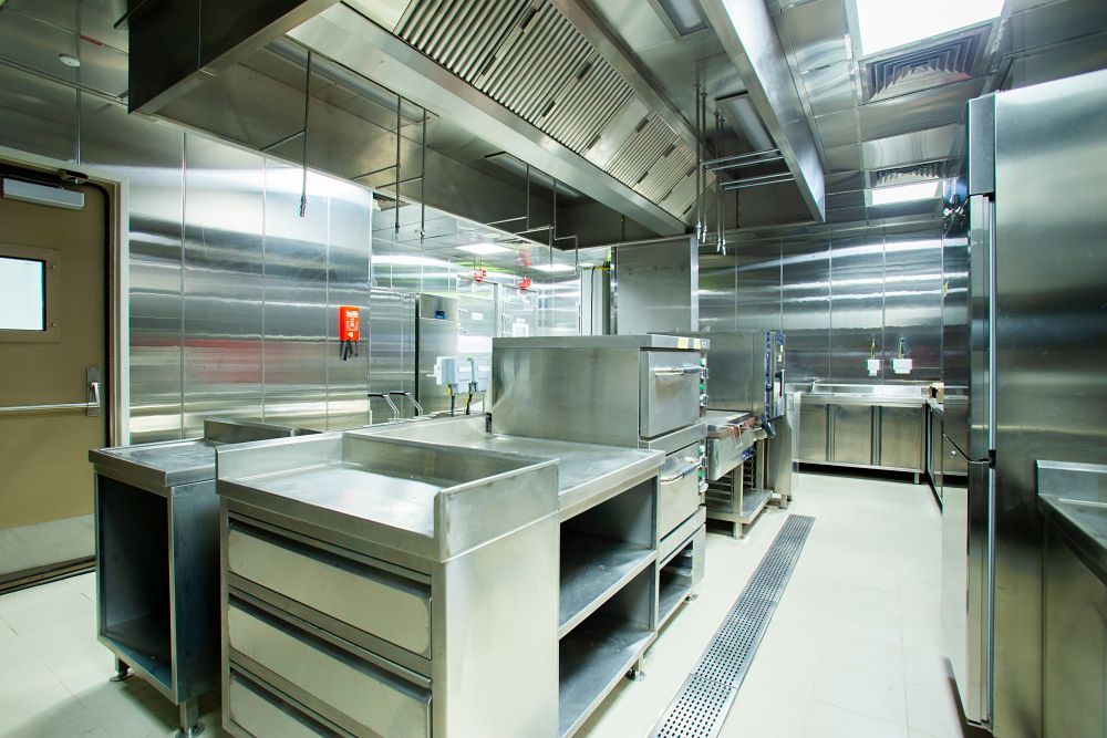 Commercial kitchen with stainless steel appliances and ventilation hood.