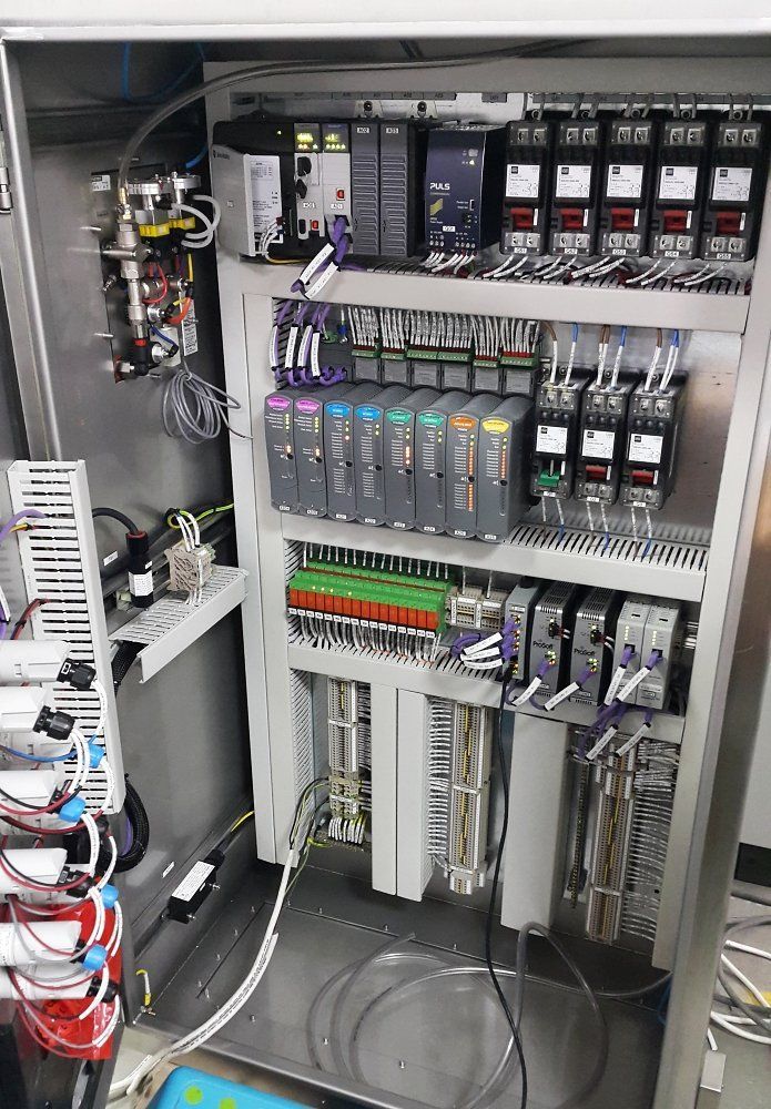 Open electrical control cabinet with relays, wiring, and circuit modules inside.