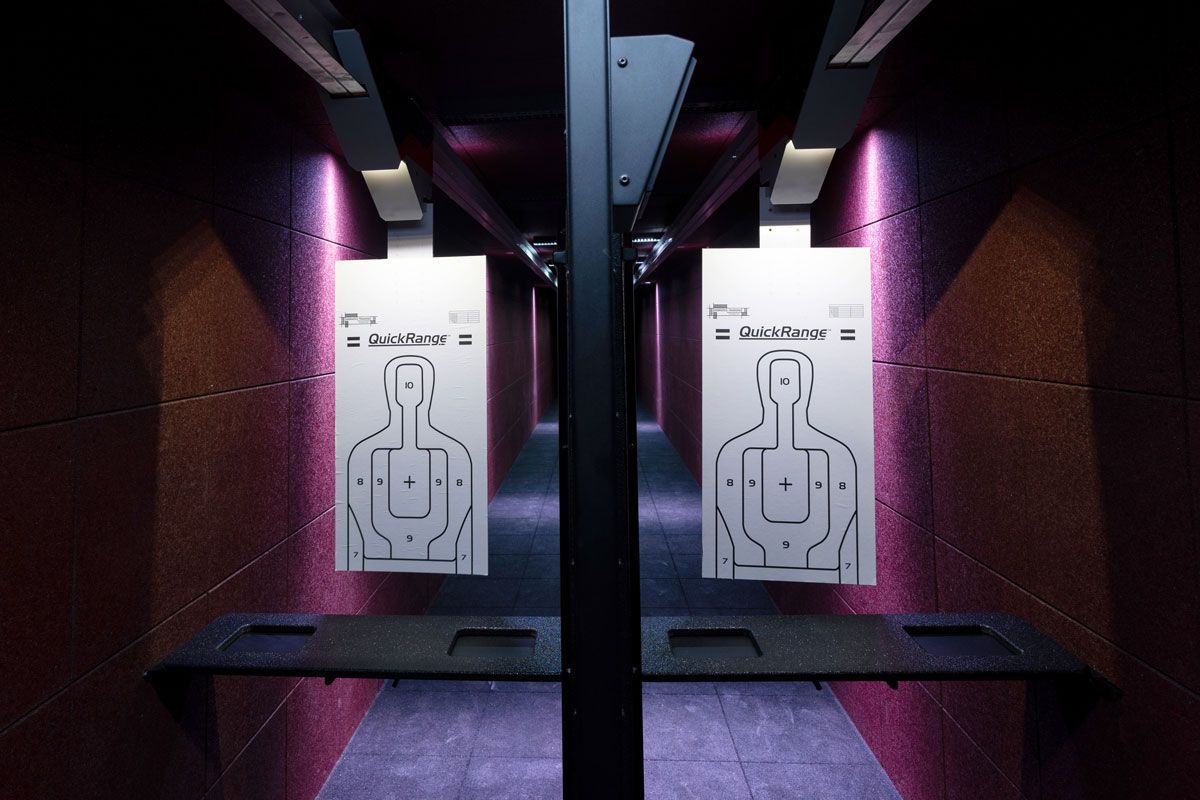 Indoor shooting range with two illuminated target boards and pink-purple lighting