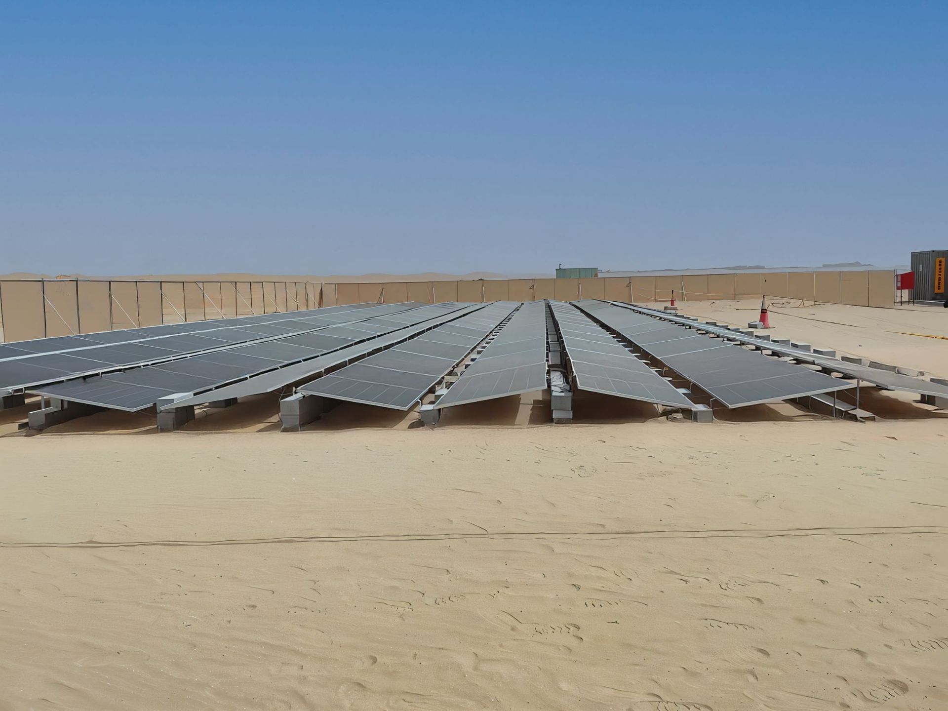 Solar panels array in a desert with a clear blue sky and a long fence in the background installed by Centurion Middle East and North Africa