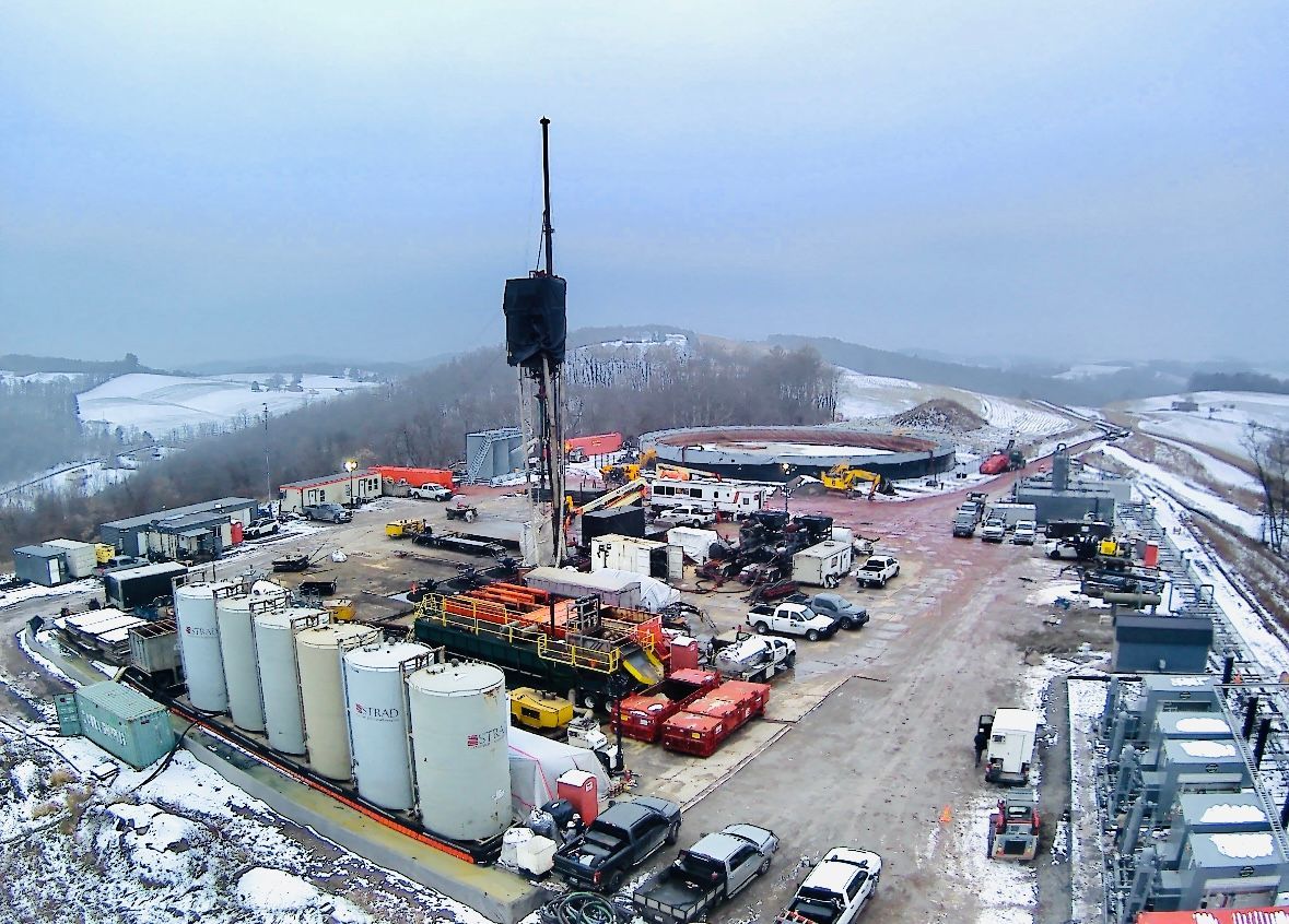 Drilling rig, tanks, trucks, and snow-covered ground in winter. Showing the Sandcat in use