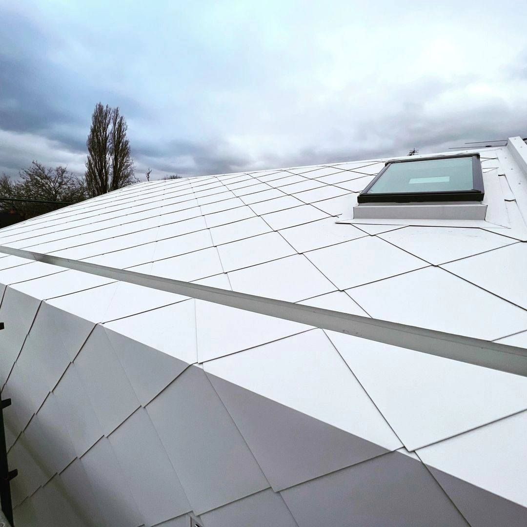 White geometric roof with a skylight, cloudy sky.