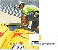 Construction worker installing insulation on a roof. Yellow insulation, wearing a hard hat, kneeling.