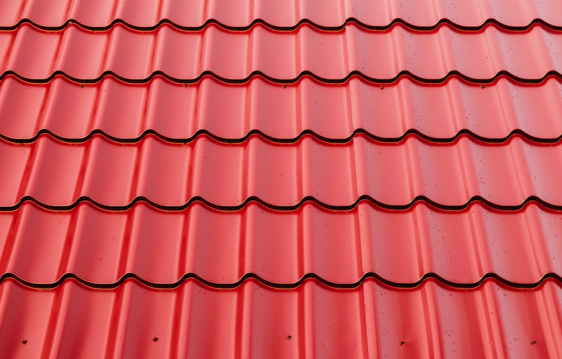 A close-up of new red metal tiles on a roof.