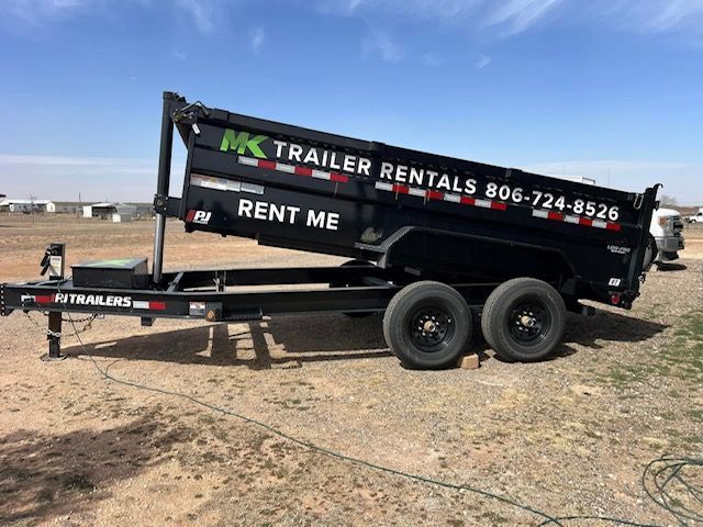 A dump trailer with the words `` rent me '' written on it is parked in a dirt field.