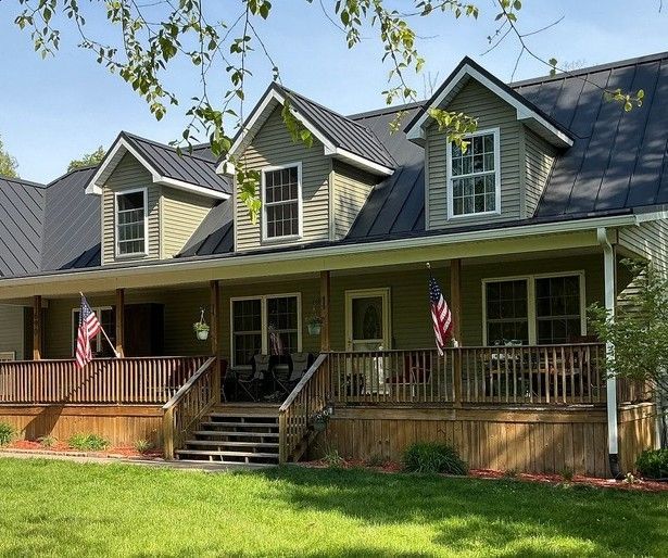 Two-story house with blue-gray siding, white trim, and navy shutters. A sunny day with green lawn and trees.
