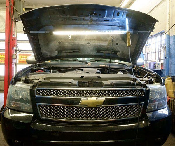 A black chevy truck with the hood open in a garage
