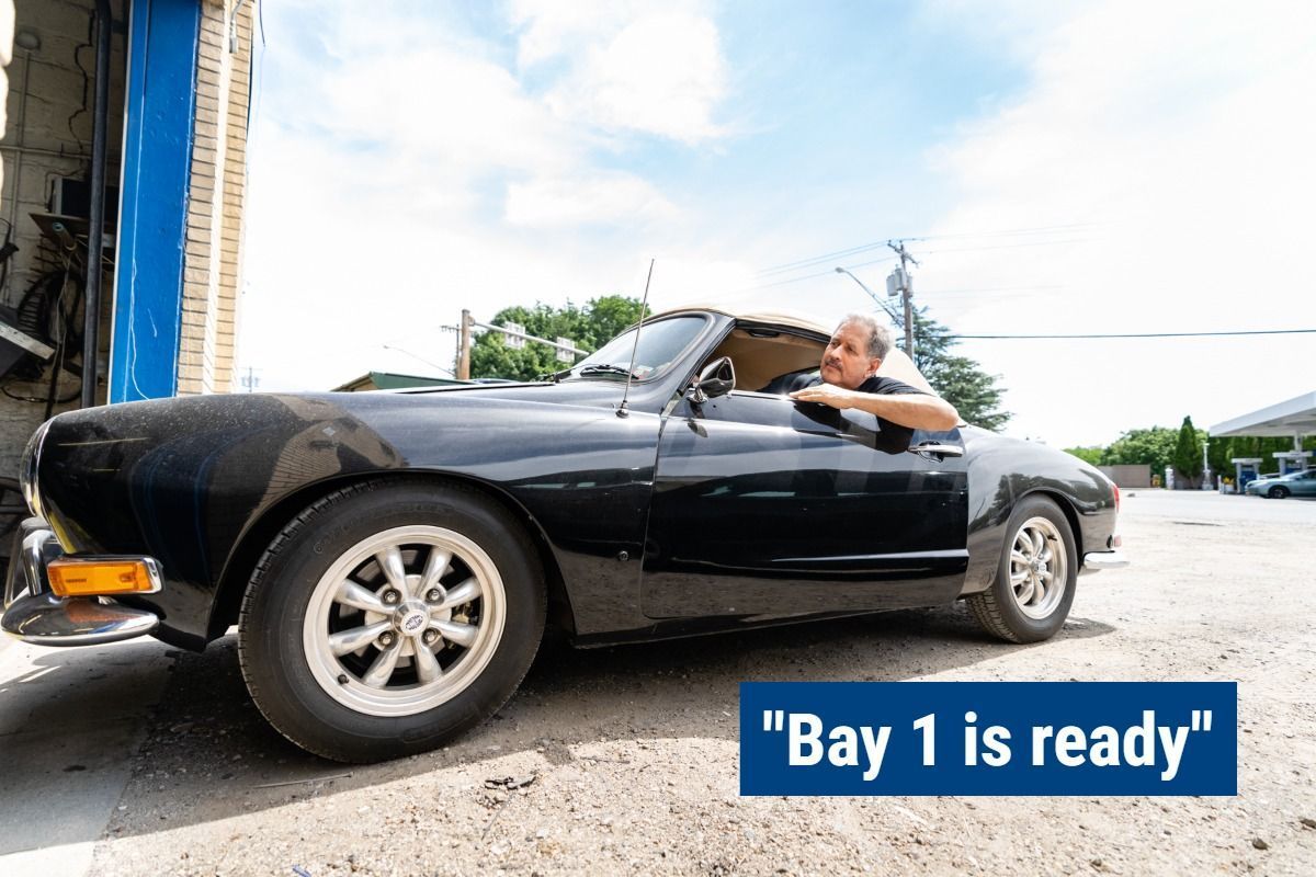 A man is driving a black car with a sign that says 