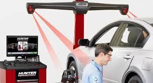 A man is standing next to a car that is being adjusted by a machine.