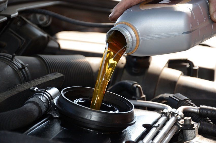 A person is pouring oil into a car engine.
