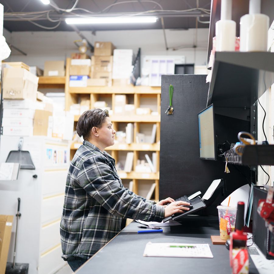 A man in a plaid shirt is typing on a keyboard