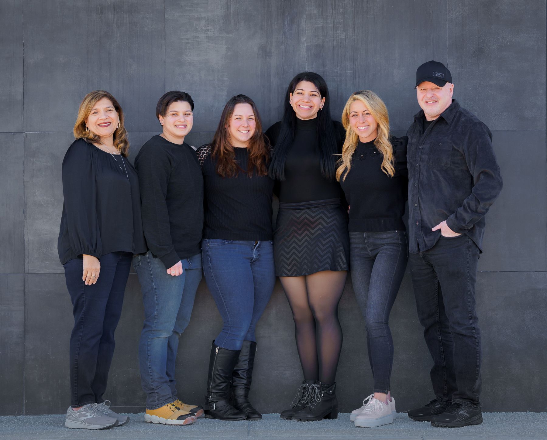 A group of people standing next to each other in front of a wall.