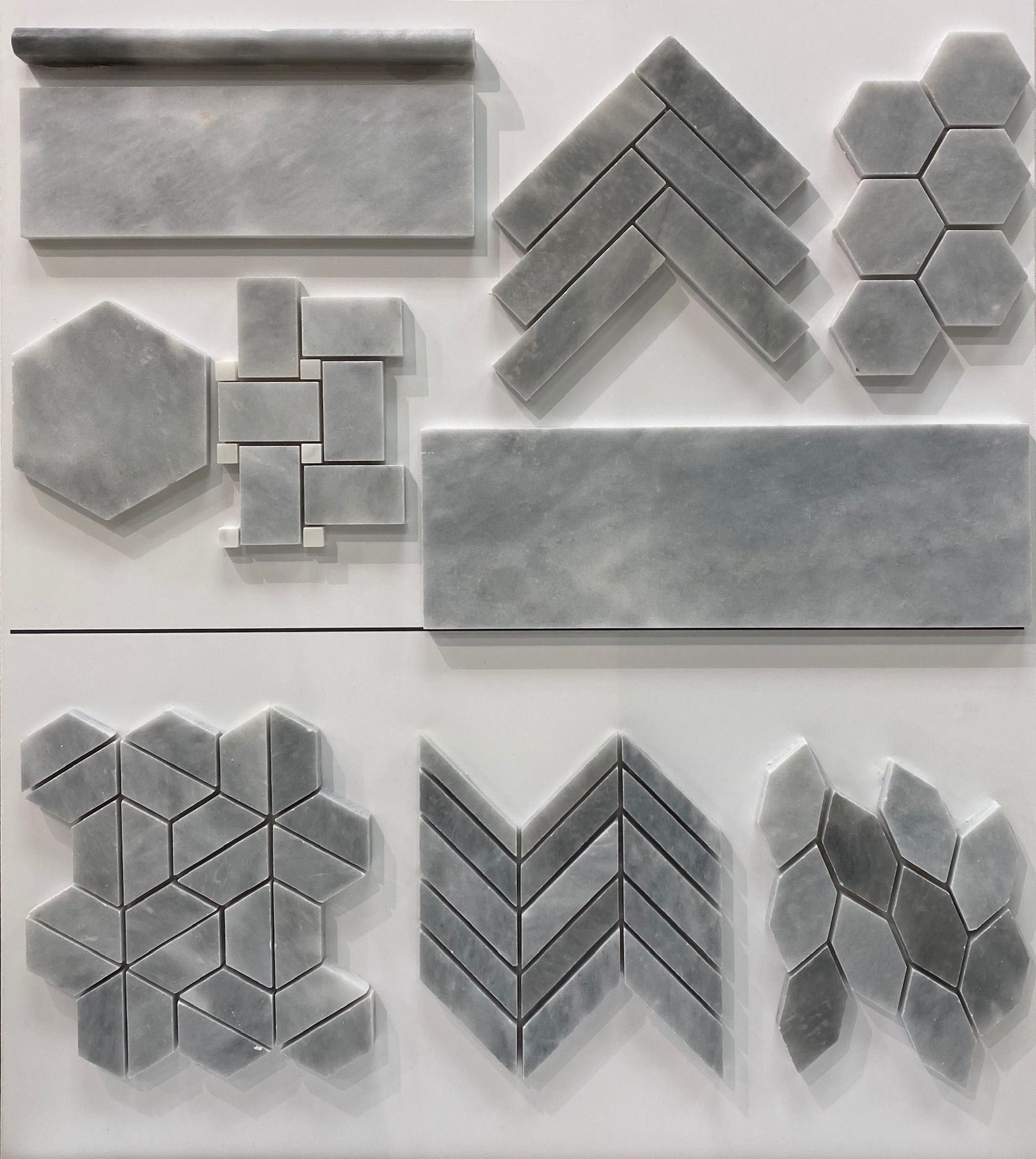 A variety of gray tiles are displayed on a white surface