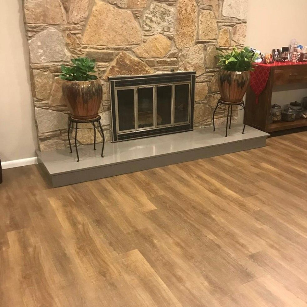 A living room with a fireplace and two potted plants.