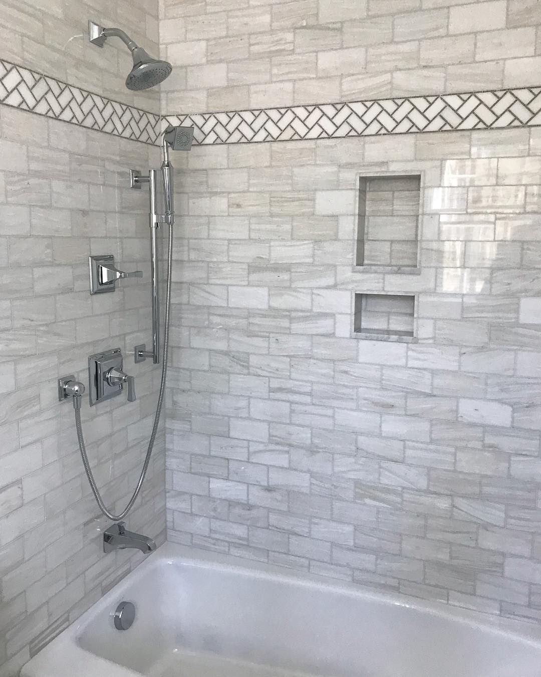 There is a bathtub in the shower with a shower head.