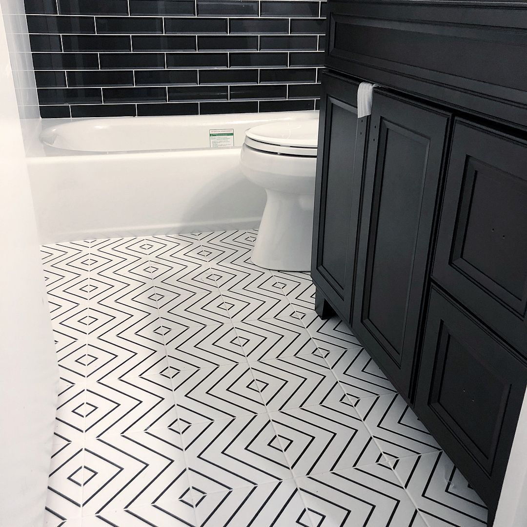 A bathroom with a black and white tile floor and a toilet.