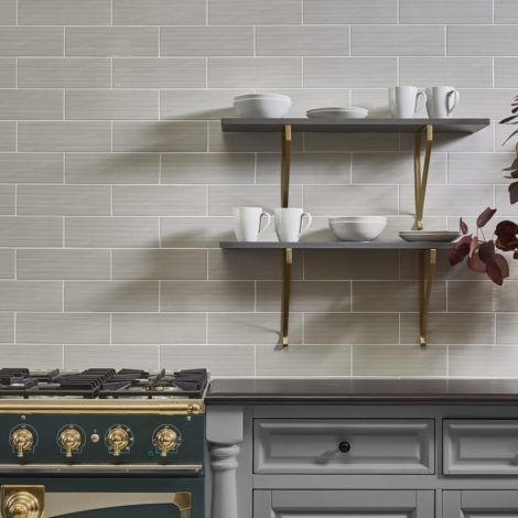 A kitchen with a stove and shelves with cups and bowls on them.