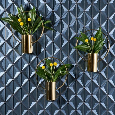 Three vases with flowers in them are hanging on a wall.
