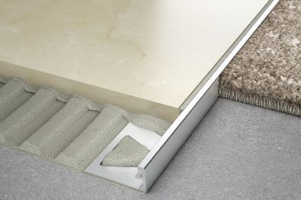 A close up of a tile floor with a metal trim.