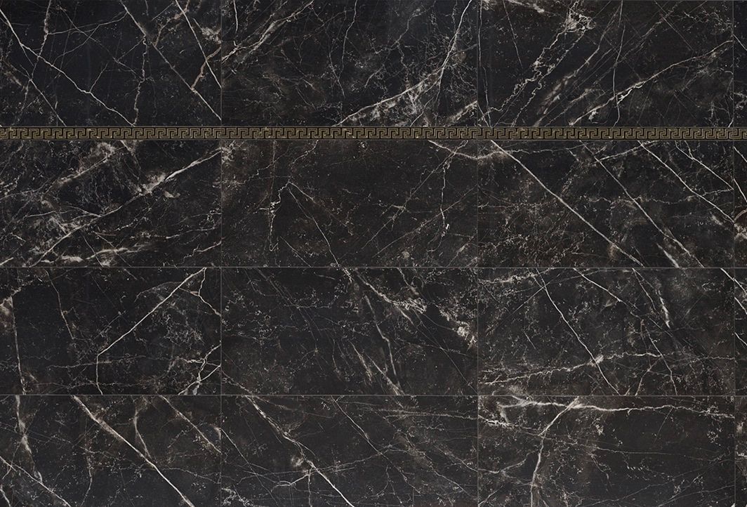 A close up of a black marble tile with a gold border.