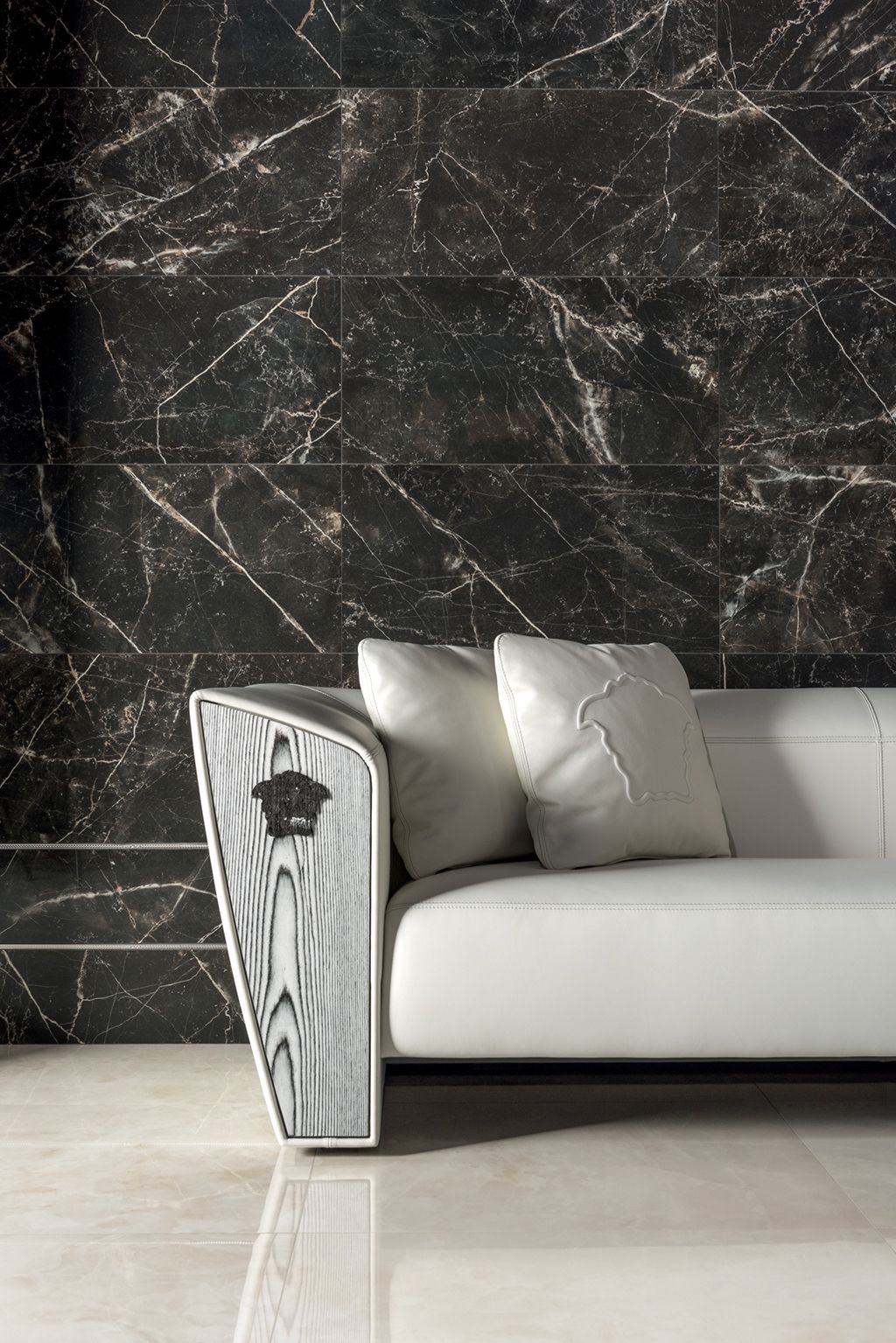 A white couch is sitting in front of a black marble wall.