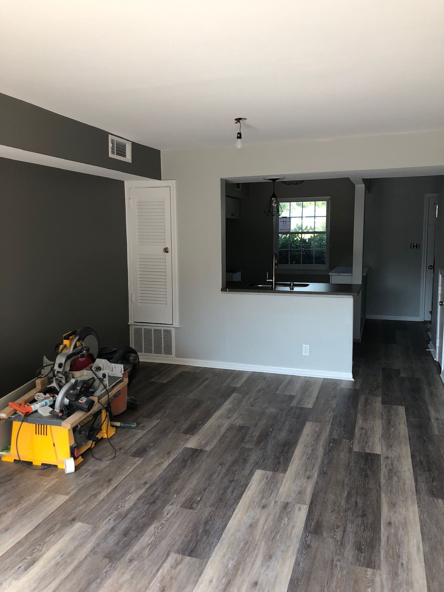 A living room with hardwood floors and a yellow box on the floor.