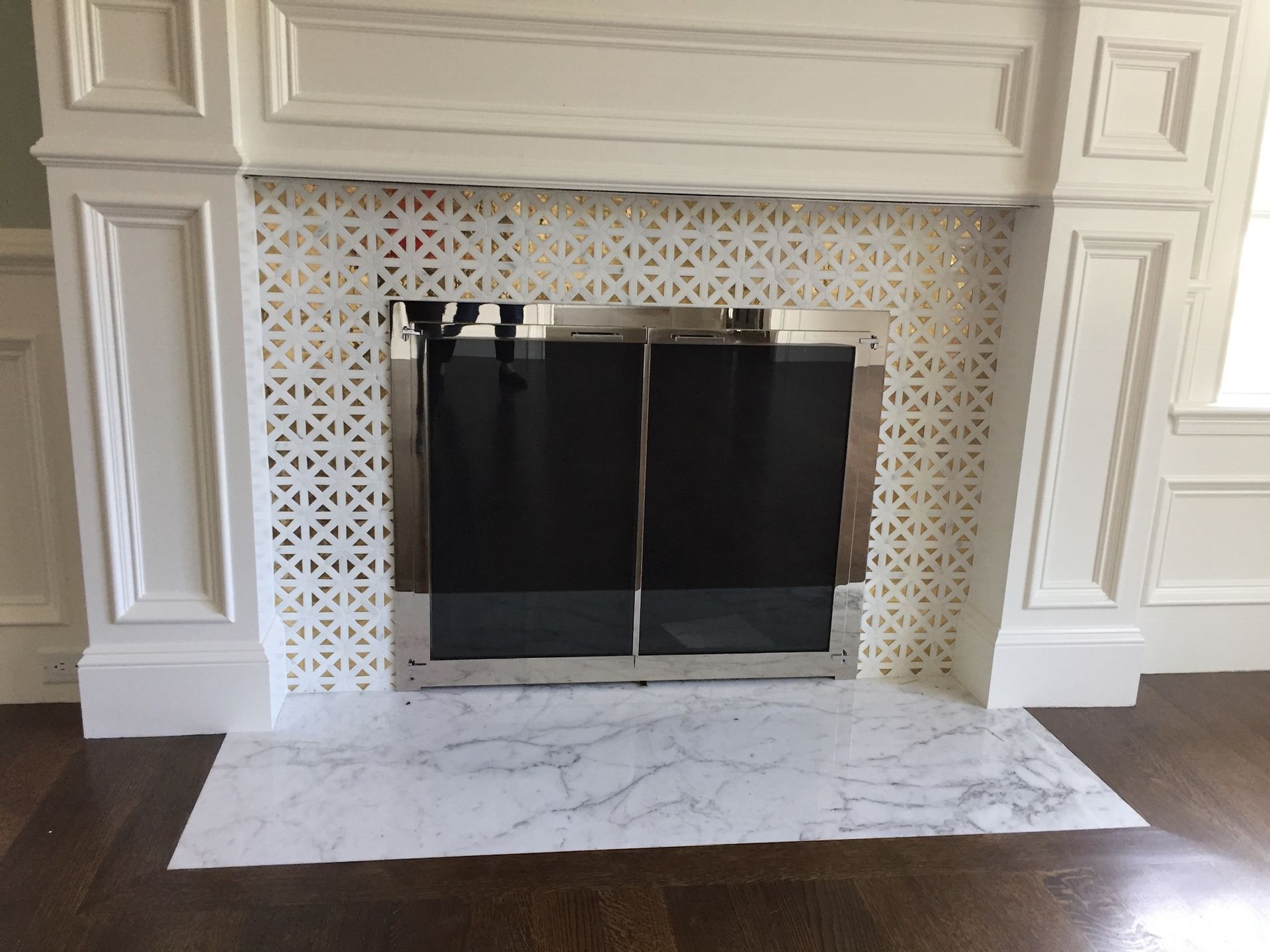 A fireplace with white tiles and a black screen