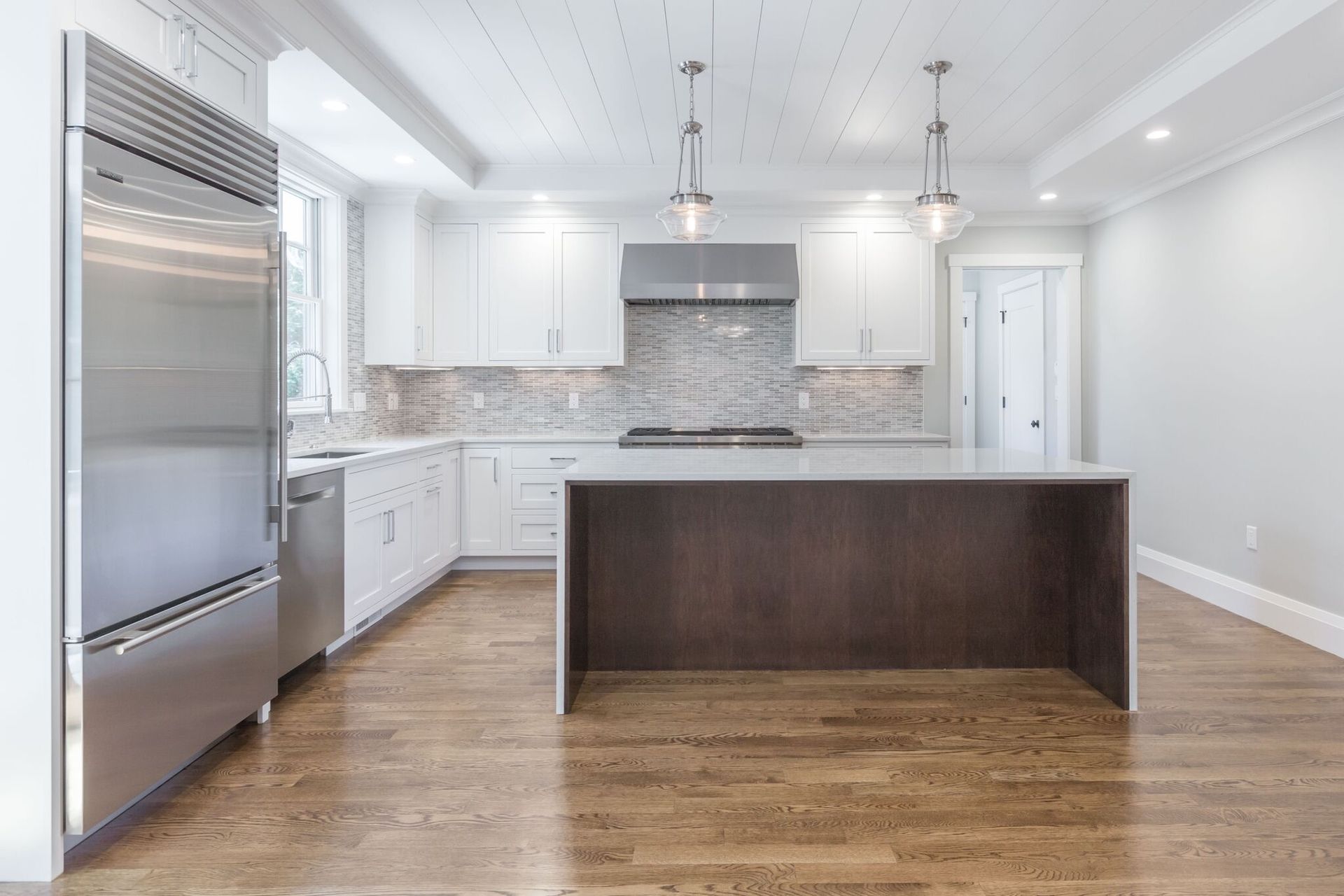 A kitchen with white cabinets , stainless steel appliances , and a large island.