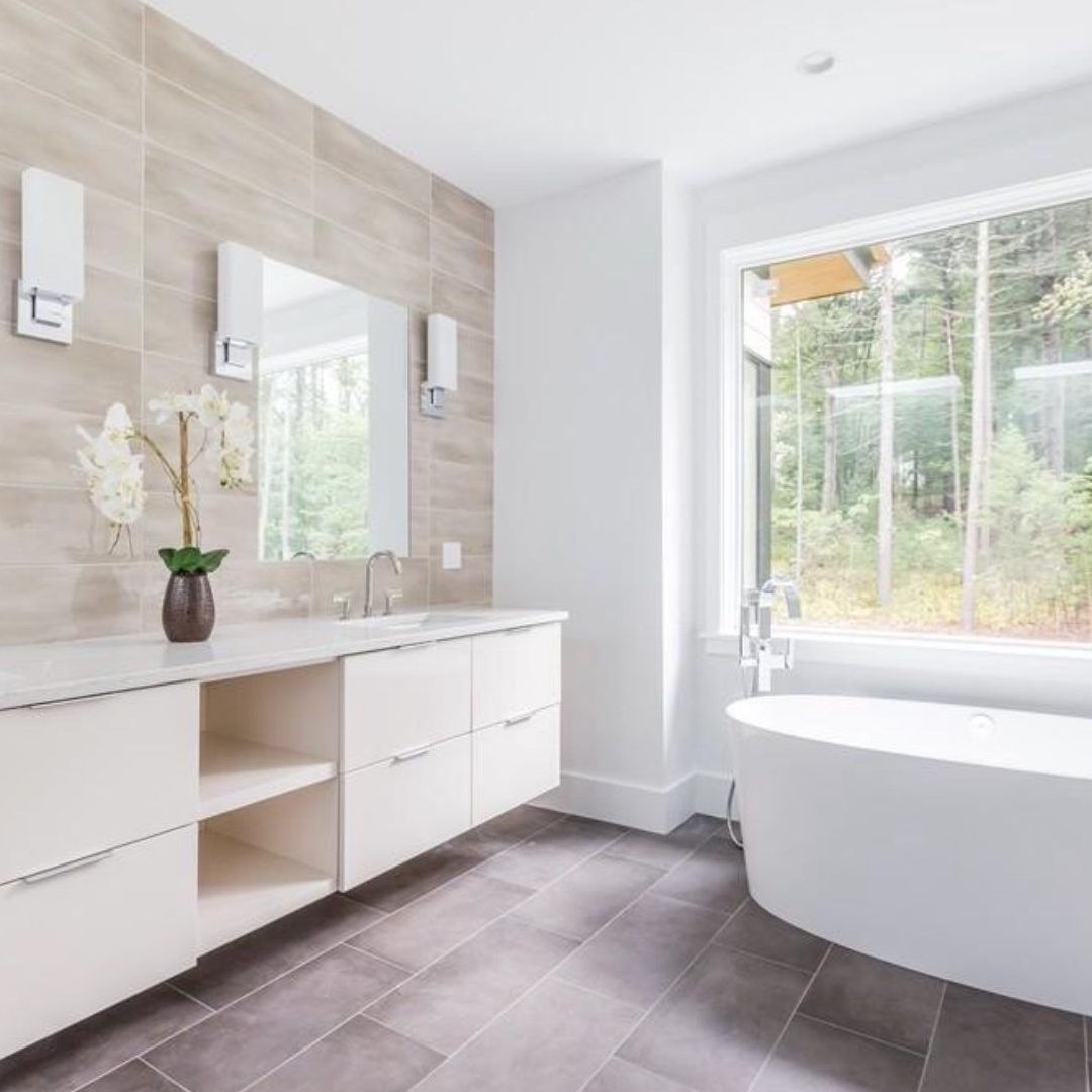 A bathroom with a tub , sink , mirror and window.