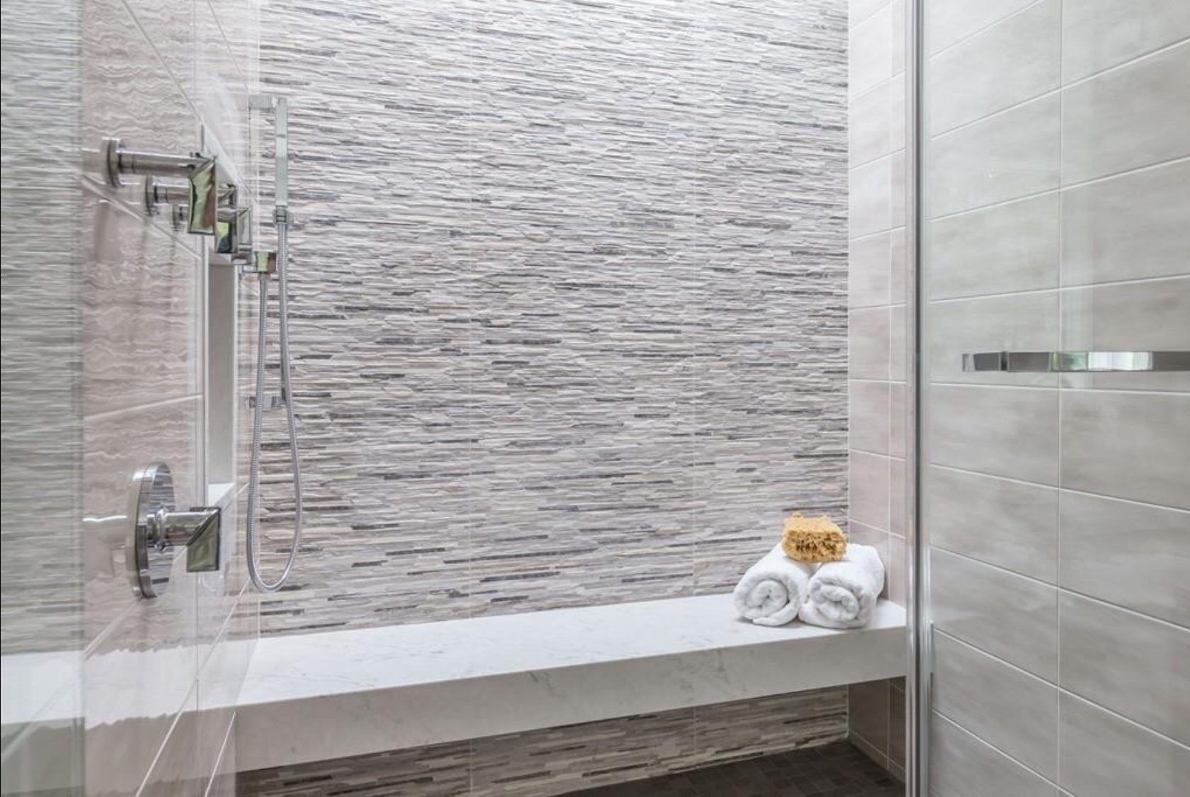 There is a bench in the shower with towels on it.