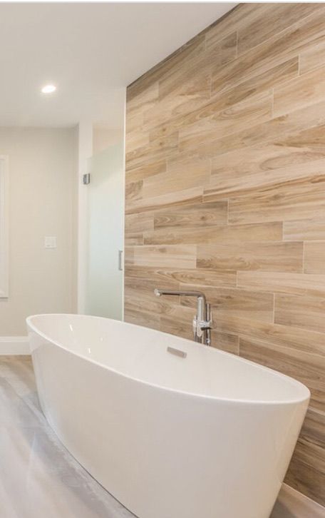A bathroom with a bathtub and a wooden wall.